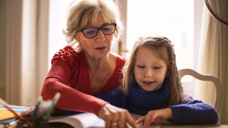 Grandmother reading while child tracks along